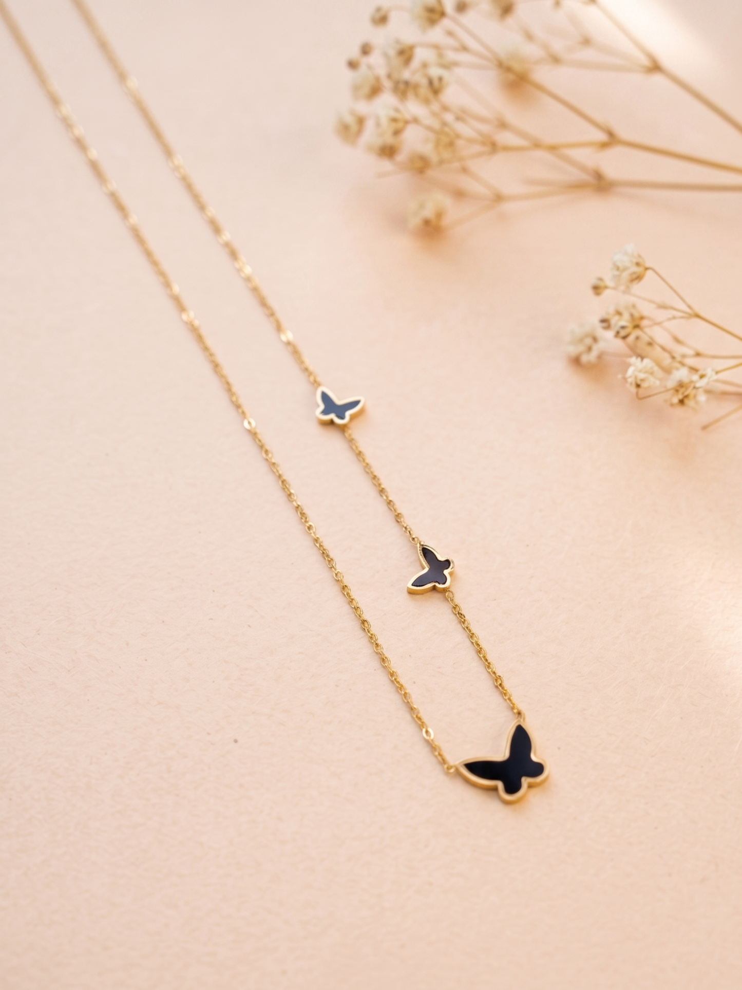 Gold necklace with butterfly pendants on a beige background