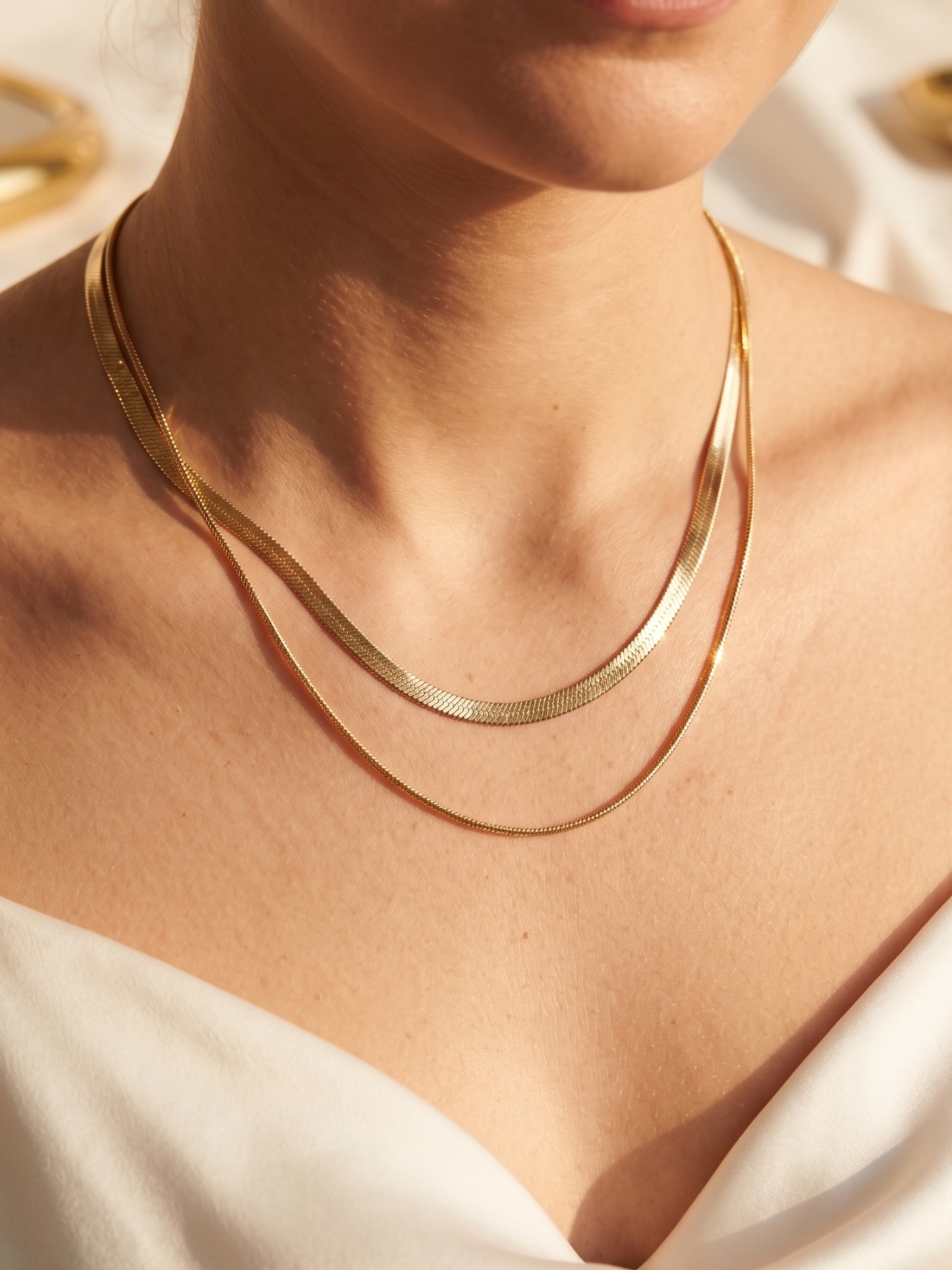 Gold necklace on a person wearing a white top
