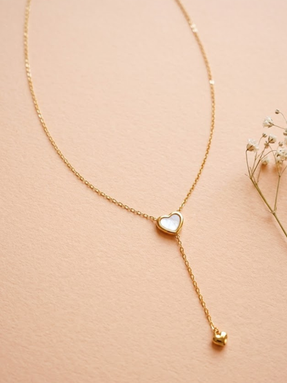 Gold necklace with a heart-shaped pendant on a beige background