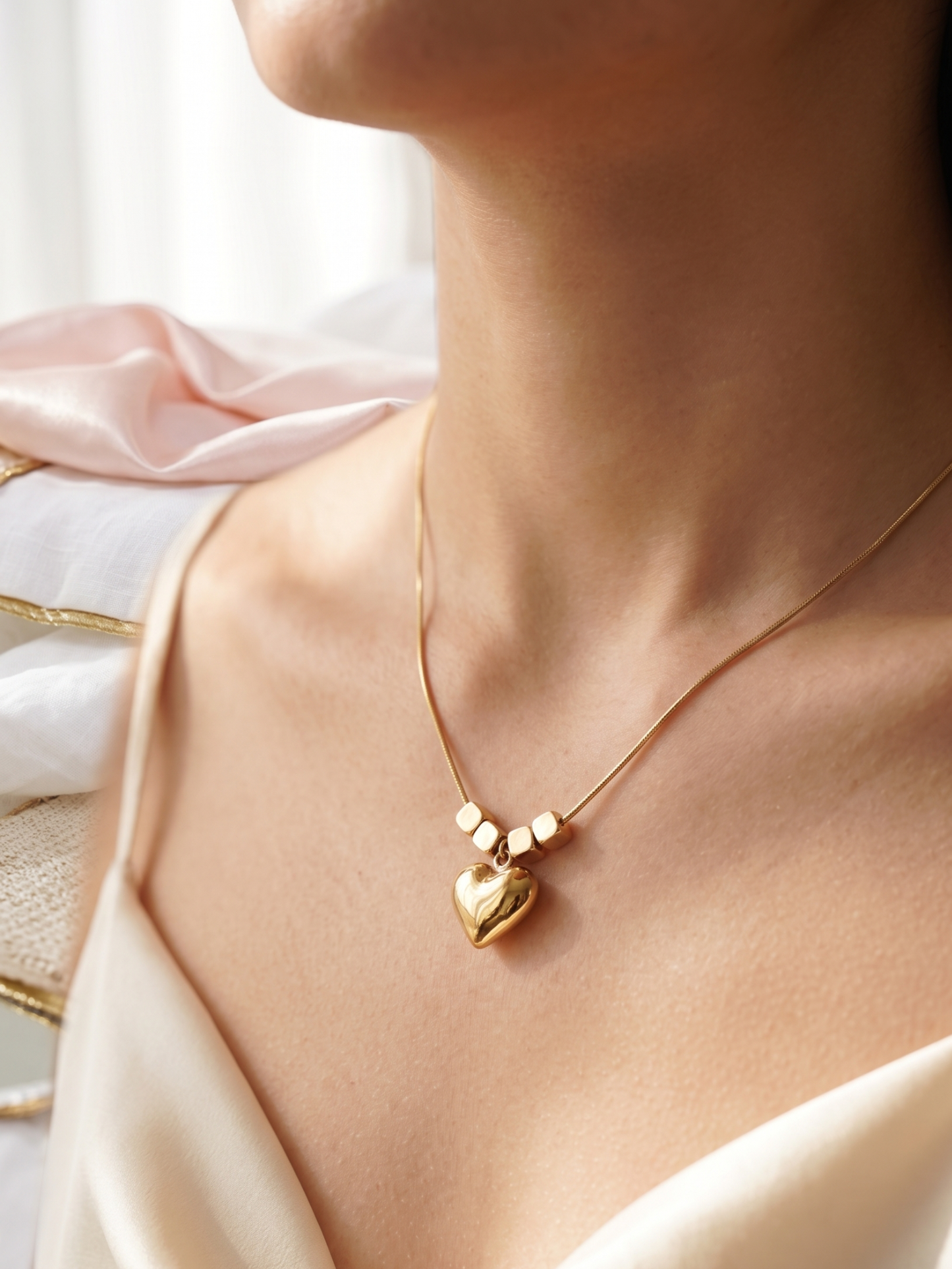 Gold necklace with a heart pendant worn by a person, with a soft background.