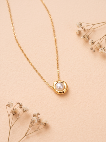 Gold necklace with a pearl pendant on a beige background
