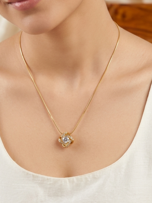 Gold necklace with a pendant on a person wearing a white top.